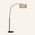 Arc floor lamp with slim black metal arm curving from a round marble base, holding a woven rattan drum shade overhead.
