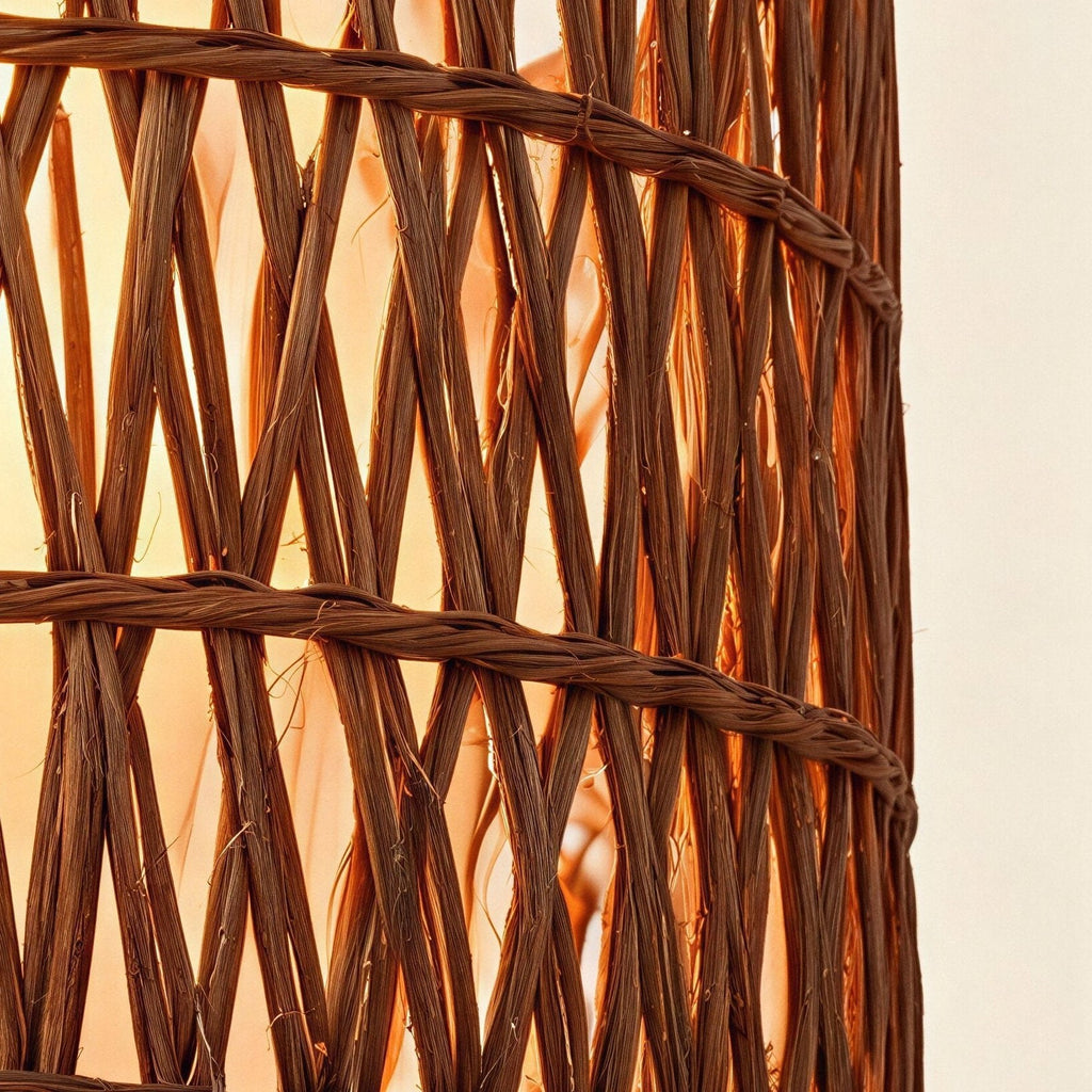 Close-up of the double-woven rattan drum shade showing crosshatched reed strands and warm light glowing through the open weave.