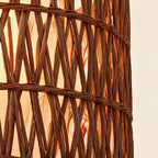 Close-up of the double-woven rattan drum shade showing crosshatched reed strands and warm light glowing through the open weave.