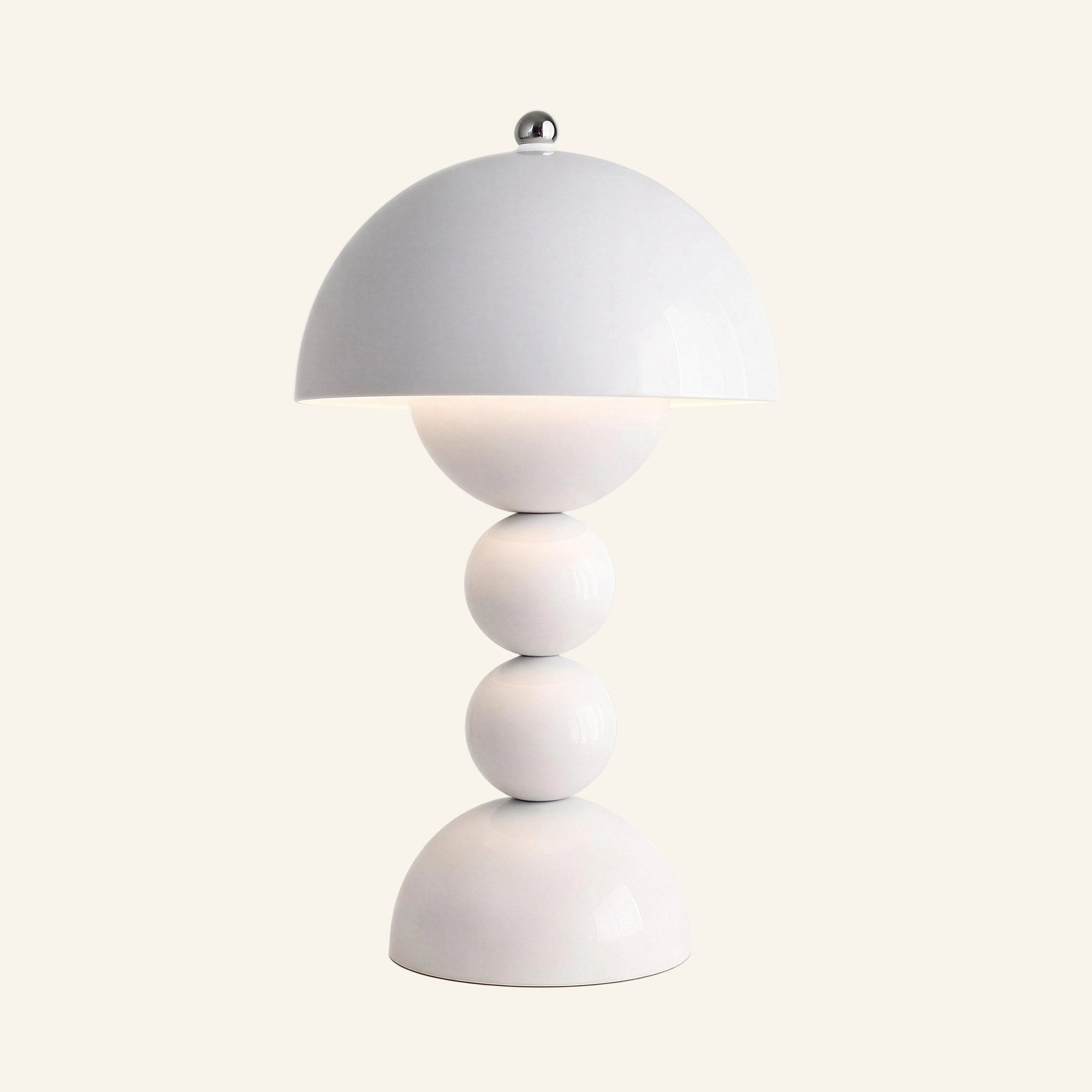 Glossy white mushroom dome table lamp with chrome finial, stacked sphere stem and half-dome base, lit on a cream backdrop