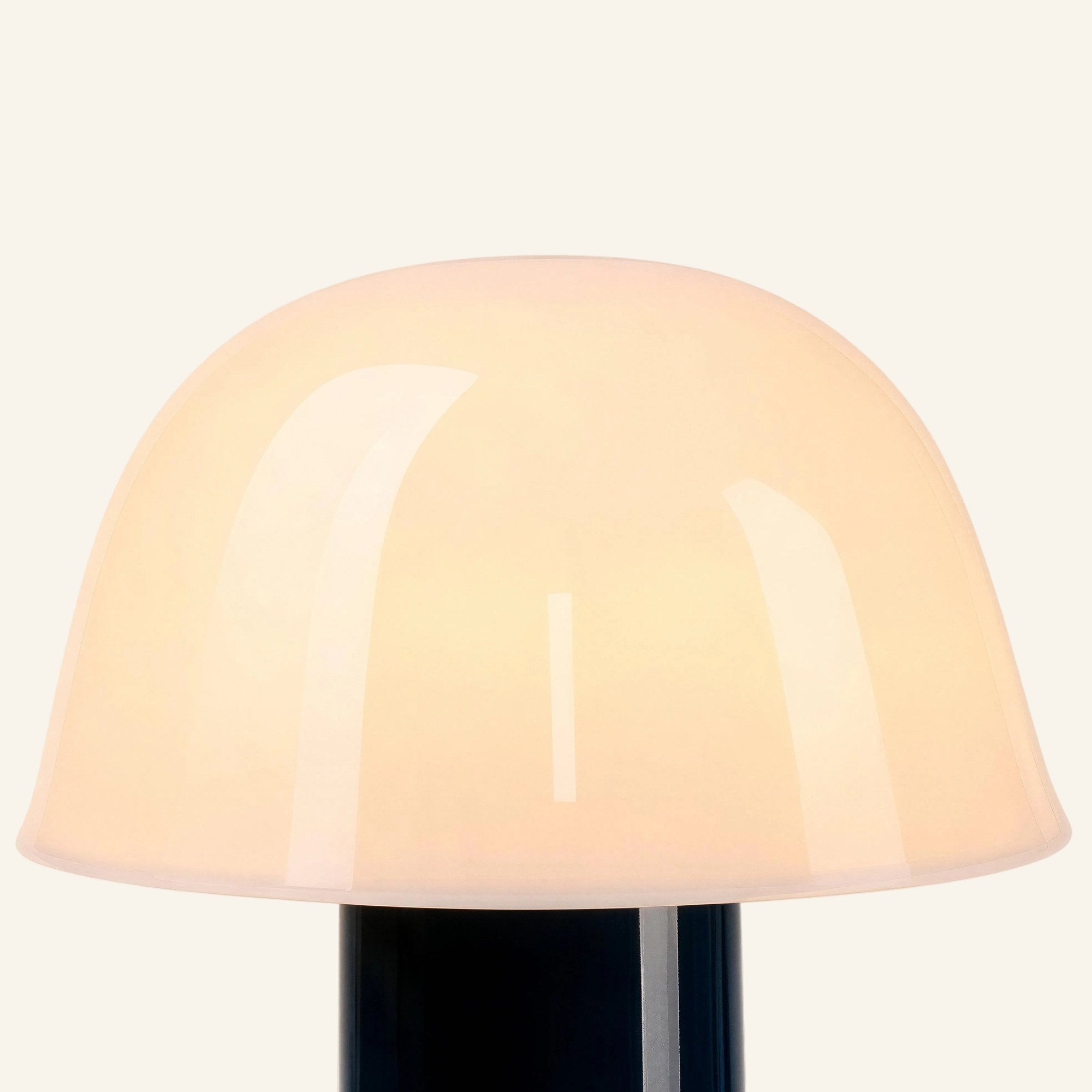 Close-up of the mushroom-shaped opal glass shade showing soft internal glow and glossy surface meeting the deep navy metal stem