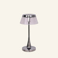 Chrome cordless table lamp with smoked acrylic drum shade and slender tapered stem on a round polished base, studio cream backdrop