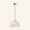 Double glass dome pendant with clear outer shell and opal inner diffuser suspended from brushed brass canopy on cream backdrop
