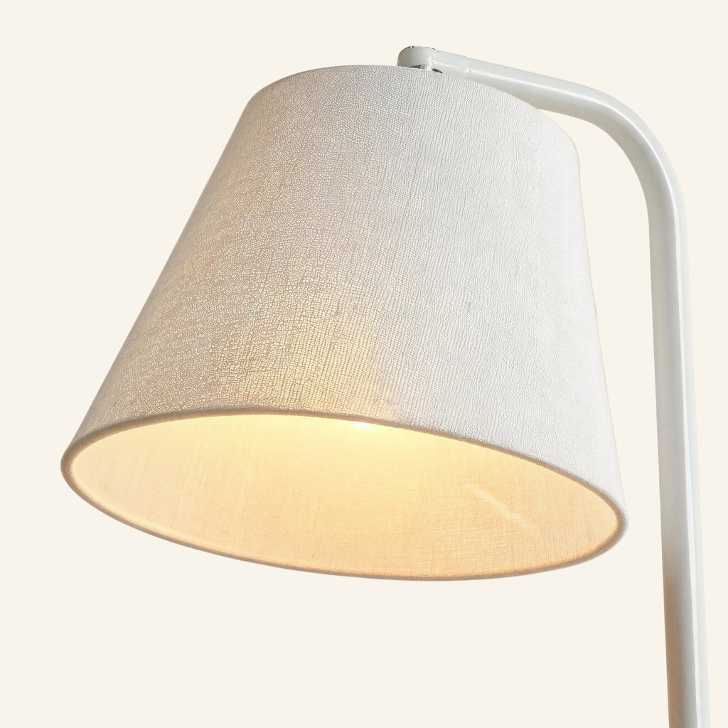Close-up of the tapered linen-look shade glowing warm white, showing fabric weave and powder-coated steel arm above bamboo top.