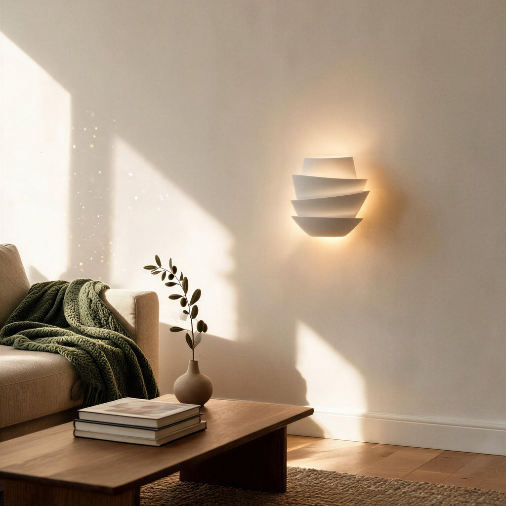 Petal wall sconce glows warmly in a sunlit living room above a wooden coffee table with olive sprig, books, and green throw
