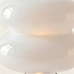 Close-up of glossy opal glass double-disc shade glowing warm at the seam, showing smooth reflections and milky diffusion