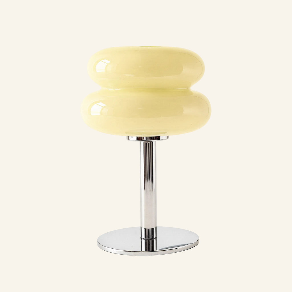 Pale butter-yellow stacked glass shade with chrome pedestal base, retro bedside table lamp seen from front against neutral background