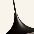Close-up of the slender spun-metal neck flaring into the curved shade, showing fine matte black texture and braided fabric cord.
