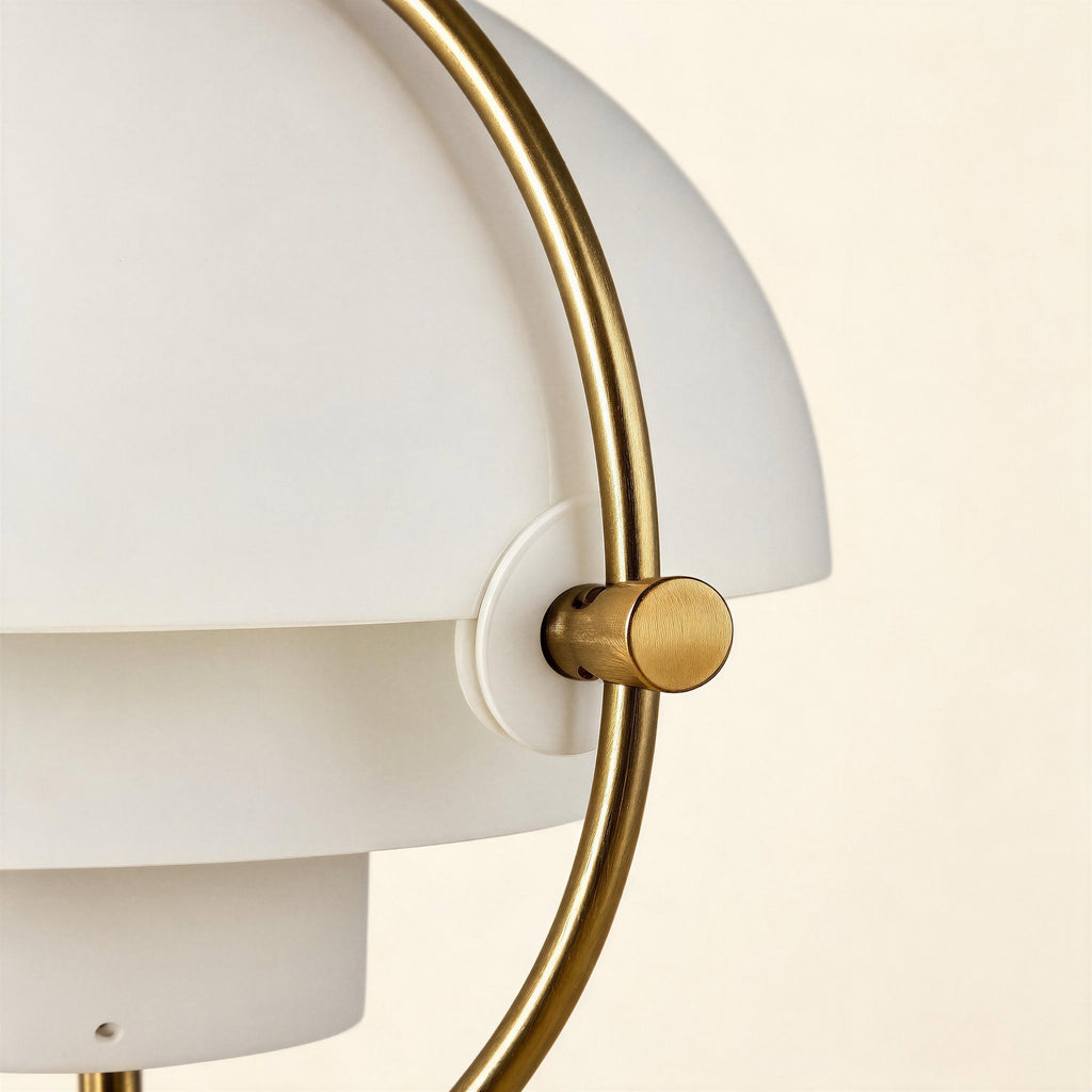 Close-up of the brass pivot knob and ring joining matte white shades, showing brushed metal grain and tiered shade construction detail.