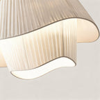 Close-up of finely pleated cream silk shade revealing the rippled wavy hem and warm glow from the inner E27 bulb