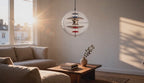 Cinematic video of a clear glass globe pendant lamp with stacked multi-color iron reflector discs glowing above a sunlit living room sofa.