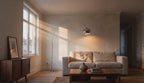 Cinematic video of a chrome arc floor lamp with dome shade glowing softly over a linen sofa in a sunlit living room.