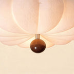 Close-up of the lamp's lower walnut sphere finial and brushed chrome collar against the softly lit ribbed paper shade.