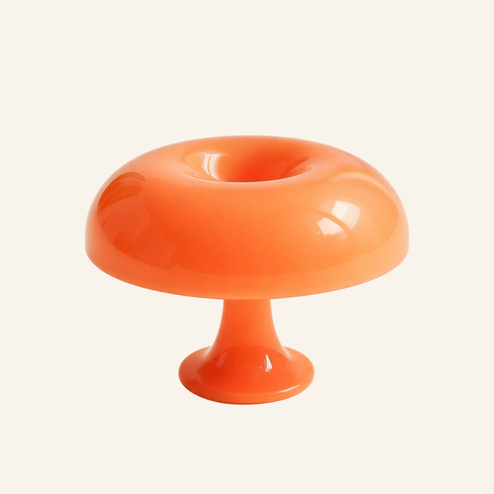 Glossy orange acrylic mushroom lamp with rounded domed shade and short pedestal base, shown against a cream studio backdrop.