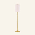 Slim floor lamp with cream linen drum shade on a slender brass-finished steel pole, round base, and pull-chain switch shown on cream backdrop.