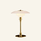 Same tiered opal glass lamp shown with polished brass stem and disc base, warm bedside light against cream backdrop.