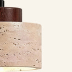 Close-up of the porous travertine drum shade with dark walnut cap, showing pitted natural stone texture and grain.