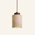 Cylindrical travertine stone pendant lamp with walnut wood cap and brown cord, warm glow at the base on cream backdrop.