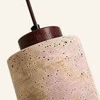 Close-up of pitted travertine shade meeting a dark walnut ring, showing porous stone texture and visible wood grain.