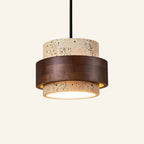 Two-tier travertine pendant lamp banded by a dark walnut wood ring, suspended from a black cord against a cream studio backdrop.