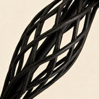 Close-up of the twisted open-cage iron column showing intertwined black metal bars and rough hand-finished surface.