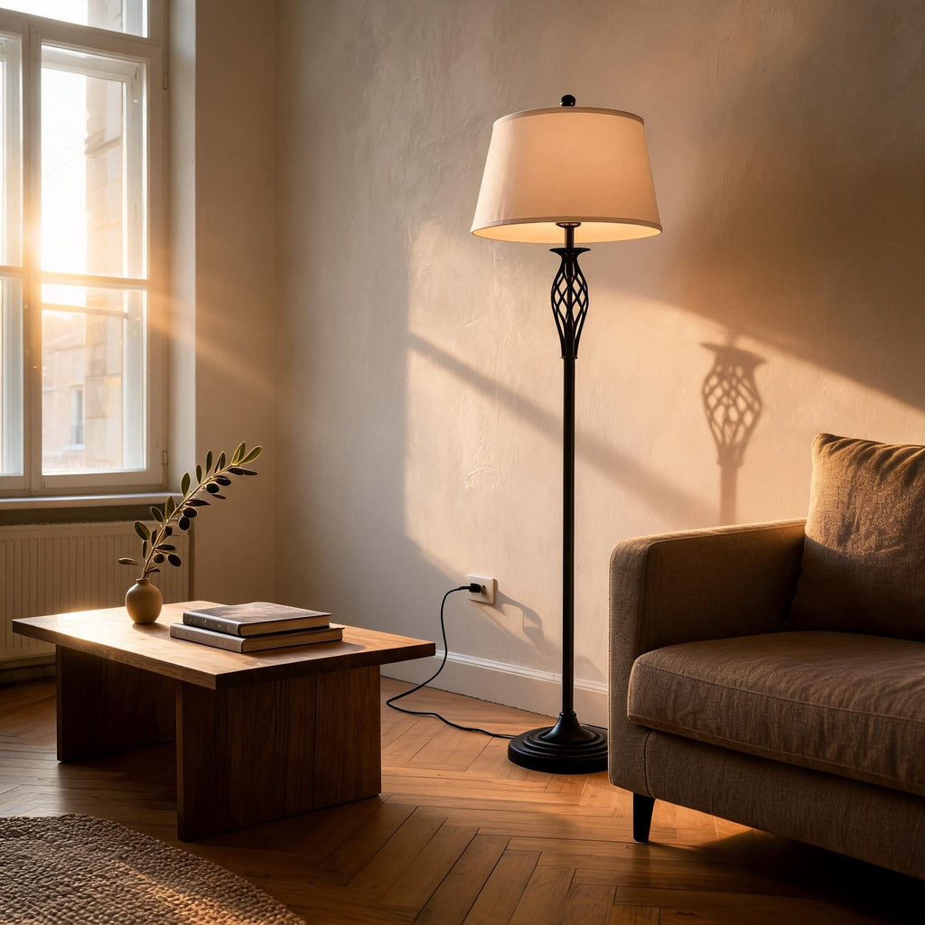 Black metal floor lamp with white shade beside a wooden coffee table in a sunlit living room with brown sofa.